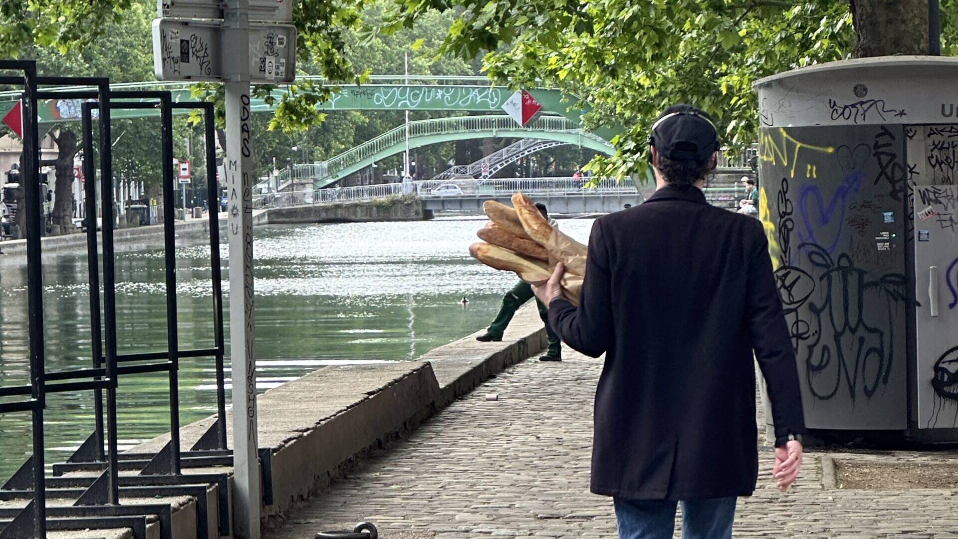 Man walking through Paris holding baguettes