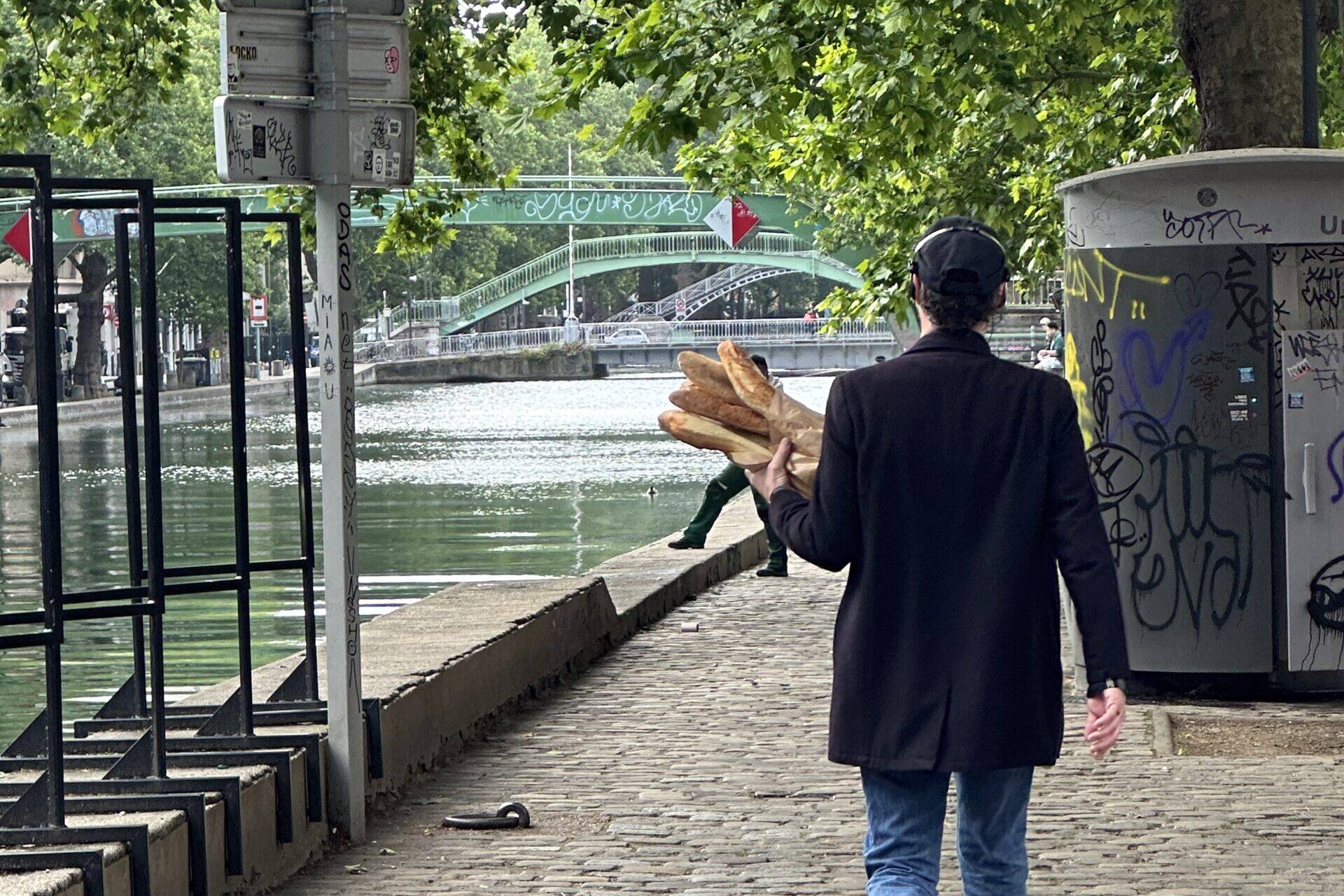 Man walking through Paris holding baguettes