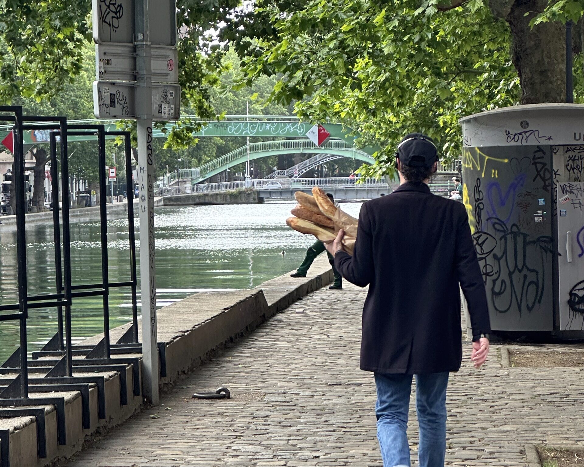 Man walking through Paris holding baguettes