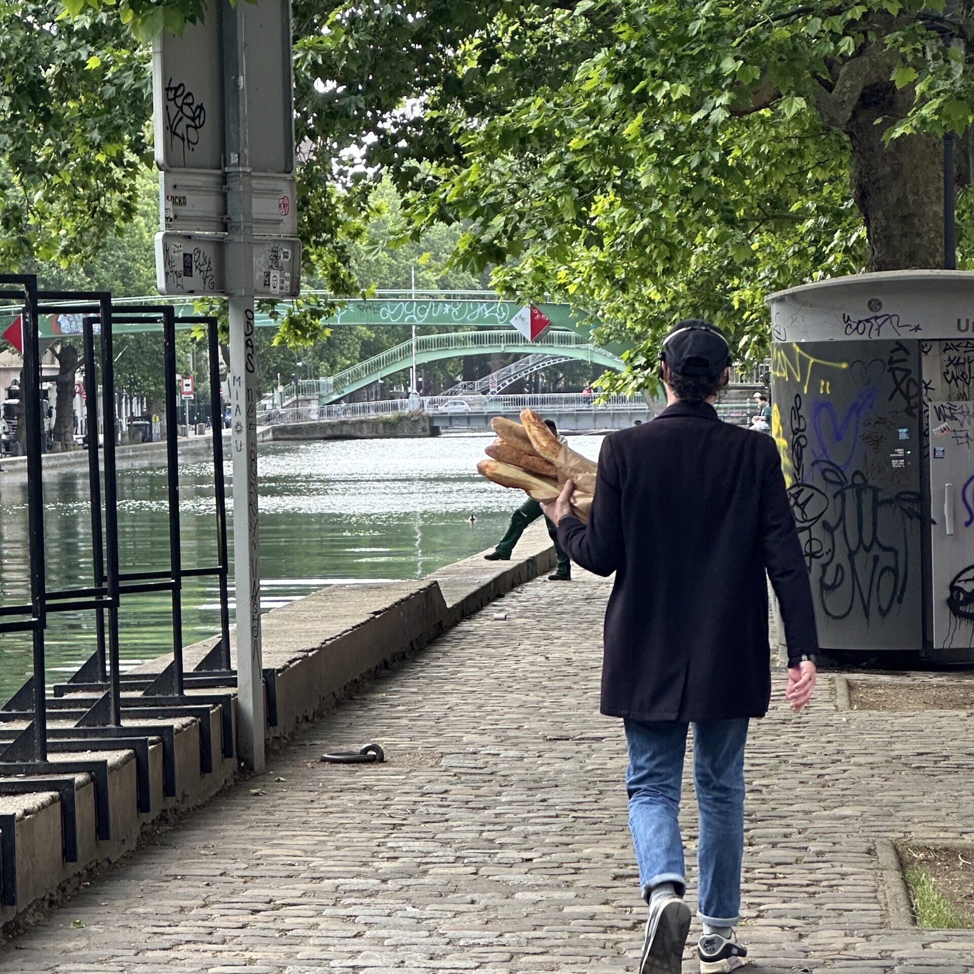 Man walking through Paris holding baguettes