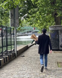 Man walking through Paris holding baguettes