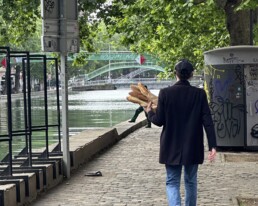 Man walking through Paris holding baguettes