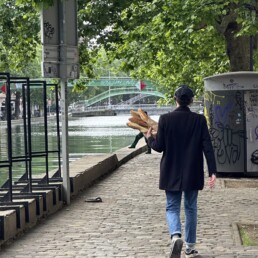 Man walking through Paris holding baguettes