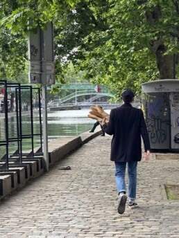 Man walking through Paris holding baguettes