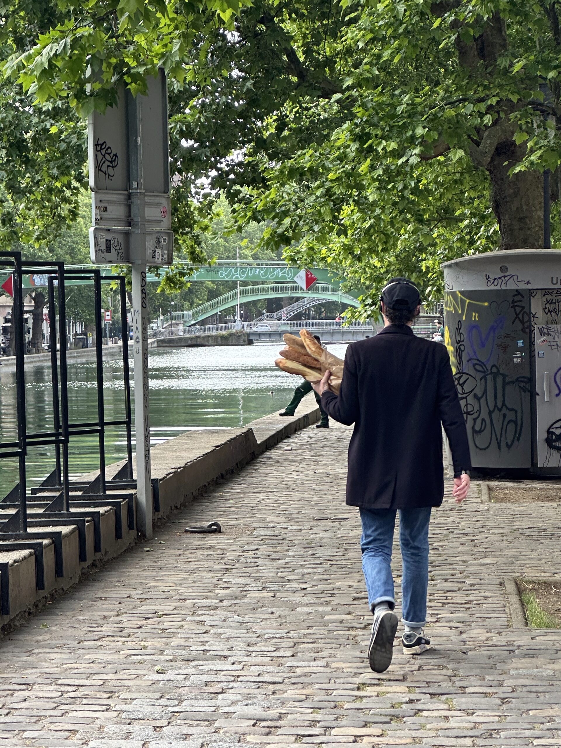 Man walking through Paris holding baguettes
